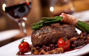 Steak premium dengan asparagus dan bacon, disajikan dengan saus merah anggur dan sayuran segar di restoran mewah
