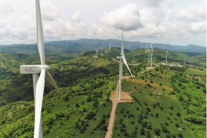 Turbin angin di perbukitan hijau sebagai bagian dari pengembangan energi terbarukan di Indonesia.