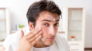 Pria sedang mengoleskan krim perawatan wajah untuk mengatasi kulit kusam secara alami