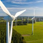 Deretan turbin angin di hamparan lahan hijau, mencerminkan perkembangan energi terbarukan untuk mendukung keberlanjutan lingkungan dan ekonomi