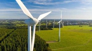 Deretan turbin angin di hamparan lahan hijau, mencerminkan perkembangan energi terbarukan untuk mendukung keberlanjutan lingkungan dan ekonomi