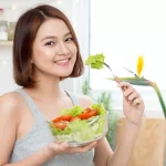 Perempuan muda menikmati salad segar sebagai bagian dari gaya hidup sehat