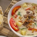 Soto Betawi khas Jakarta dengan kuah santan susu, potongan daging sapi, dan jeroan, disajikan dengan emping melinjo dan irisan daun bawang