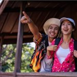 Pasangan traveler menikmati momen liburan sambil melihat pemandangan dari balkon kayu