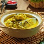 Ilustrasi gulai ikan patin khas Melayu dengan kuah santan kental dan rempah-rempah seperti kunyit, serai, dan lengkuas
