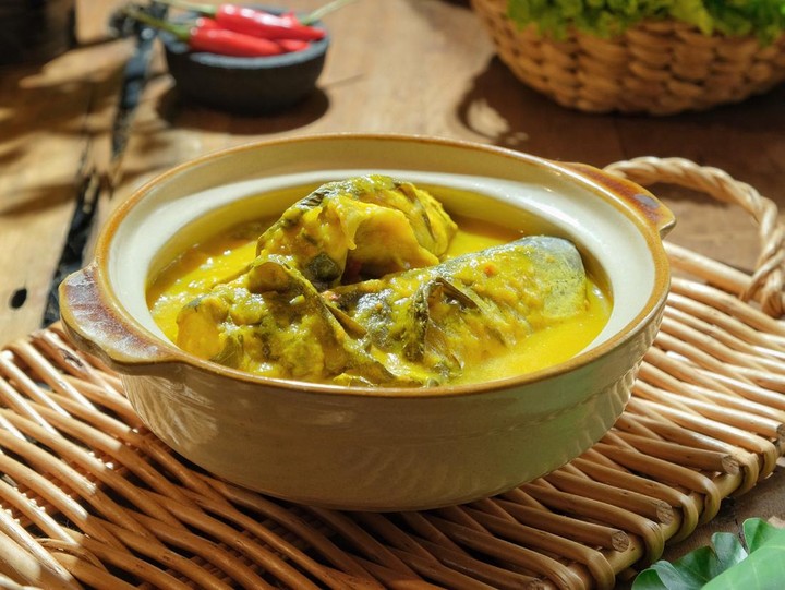 Ilustrasi gulai ikan patin khas Melayu dengan kuah santan kental dan rempah-rempah seperti kunyit, serai, dan lengkuas