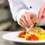 Chef menyusun garnish dalam seni plating makanan elegan di restoran fine dining