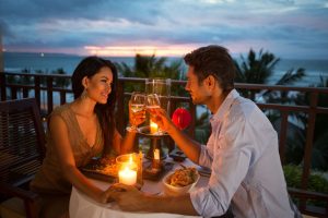 Pasangan muda menikmati makan malam romantis dengan lilin di luar ruangan