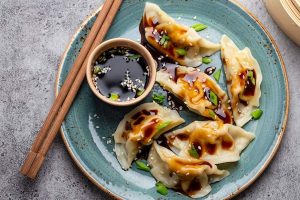 Pangsit jiaozi khas Tiongkok dengan isian daging dan sayuran, disajikan dengan saus cocolan