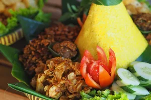 Tumpeng nasi kuning dengan hiasan sayuran segar, simbol kuliner tradisional Indonesia yang tetap relevan di era modern