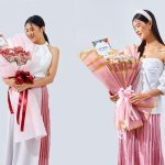 Seorang wanita memegang dua buket bunga berbalut kertas pink dari Athaya Florist