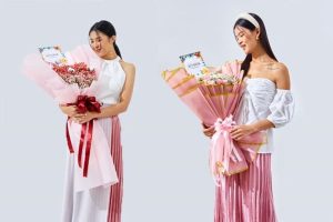 Seorang wanita memegang dua buket bunga berbalut kertas pink dari Athaya Florist