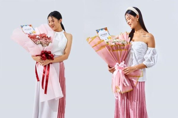 Seorang wanita memegang dua buket bunga berbalut kertas pink dari Athaya Florist